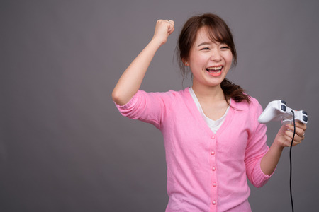 Young beautiful Asian woman playing games with game controllerの写真素材