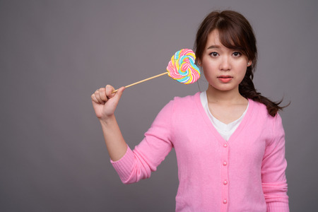 Young beautiful Asian woman holding colorful lollipopの写真素材