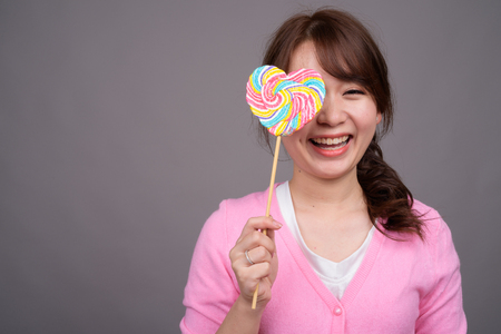 Young beautiful Asian woman holding colorful lollipopの写真素材