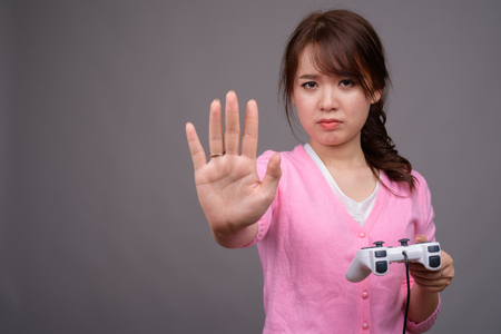 Young beautiful Asian woman playing games with game controllerの写真素材