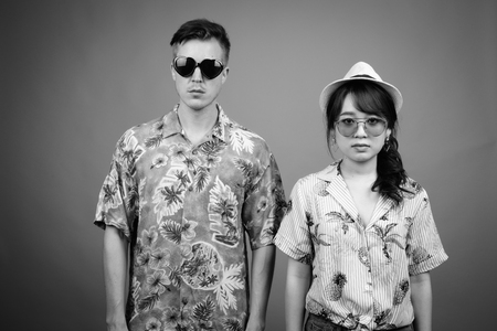 Multi ethnic tourist couple wearing sunglasses and Hawaiian shirt