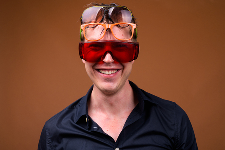 Young happy man in wet clothes smiling and wearing many sunglassesの写真素材
