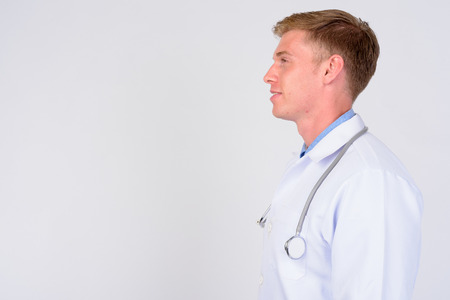 Profile view of happy young man doctor with blond hair smilingの写真素材