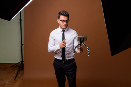 Young handsome Hispanic businessman against brown backgroundの写真素材