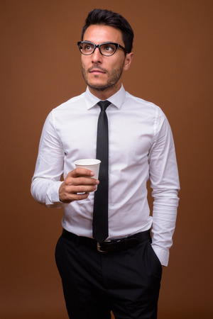Young handsome Hispanic businessman against brown backgroundの写真素材