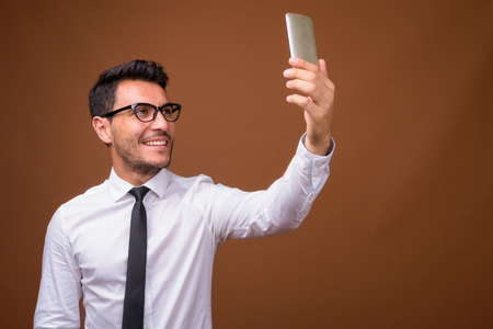 Young handsome Hispanic businessman against brown backgroundの写真素材