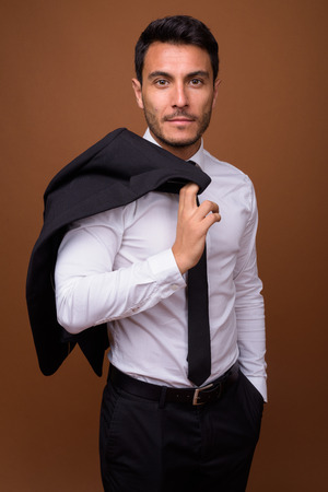 Young handsome Hispanic businessman against brown backgroundの写真素材
