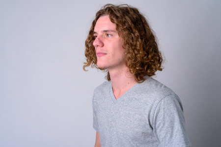 Face of young handsome man with curly hair thinkingの写真素材