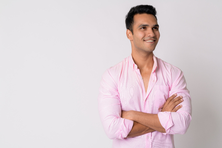 Portrait of young happy Indian businessman thinking with arms crossedの写真素材