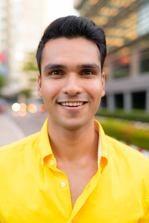 Face of young happy Indian man smiling in the city outdoorsの写真素材
