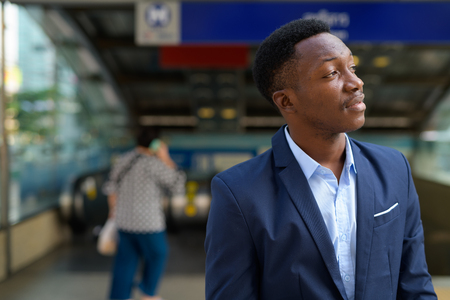 Profile view of young handsome African businessman thinking outside the subway train stationの写真素材