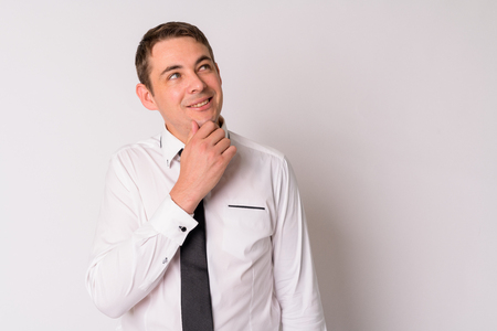 Portrait of happy handsome businessman thinking and looking upの写真素材