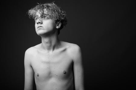 Skinny young man with curly hair shirtless against gray backgrouの写真素材