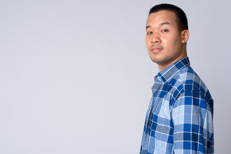 Profile view of young Asian hipster man looking at cameraの写真素材