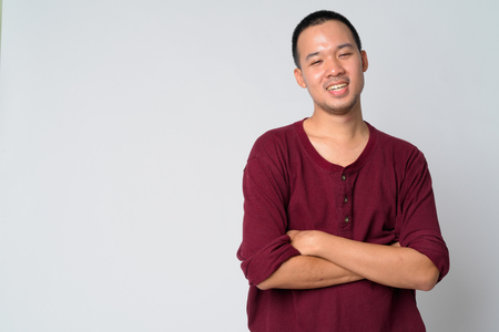 Portrait of happy young Asian man smiling with arms crossedの写真素材