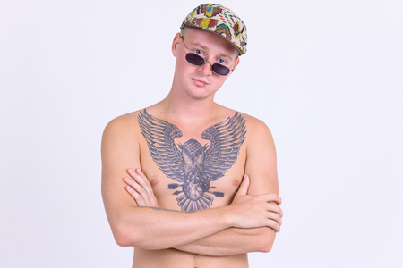 Young handsome shirtless man with tattoos crossing armsの写真素材