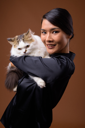 Studio shot of beautiful Asian businesswoman against brown backgの写真素材