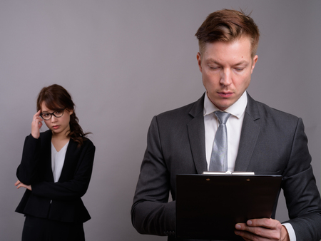 Young businessman and young Asian businesswoman against gray bacの写真素材