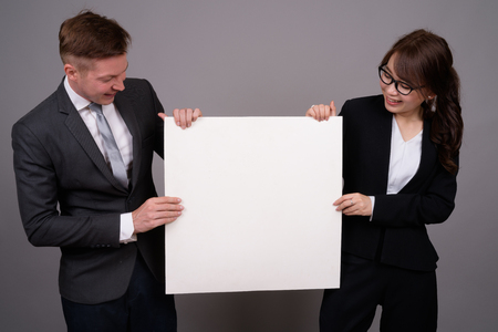 Young businessman and young Asian businesswoman against gray bacの写真素材
