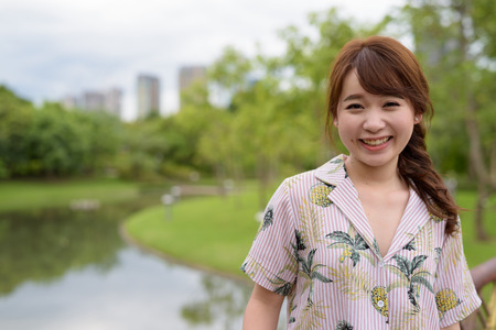 Young beautiful Asian tourist woman relaxing at the parkの写真素材