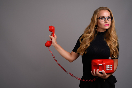 Young beautiful businesswoman with blond hair against gray backgの写真素材