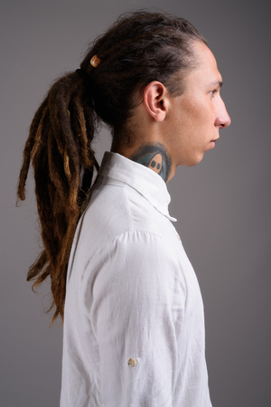 Young businessman with dreadlocks against gray backgroundの写真素材