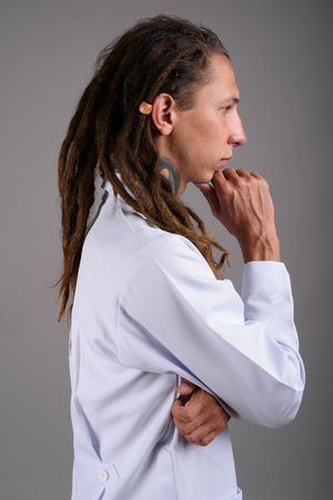 Young man doctor with dreadlocks against gray backgroundの写真素材