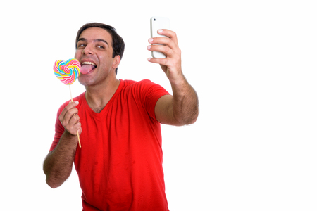 Studio shot of young happy Persian man smiling and taking selfieの写真素材