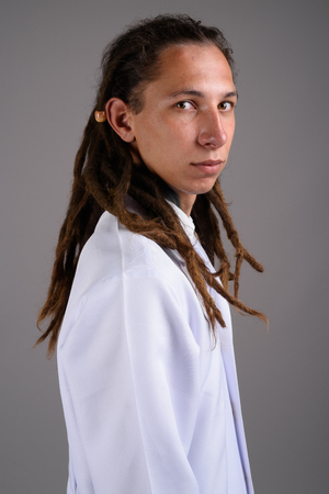 Young man doctor with dreadlocks against gray backgroundの写真素材