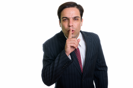 Studio shot of young Persian businessman with finger on lips isoの写真素材