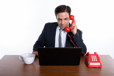 Studio shot of young Persian businessman talking on old telephonの写真素材