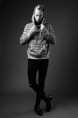 Studio shot of young handsome man against gray background in blackの写真素材