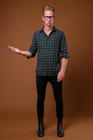 Studio shot of young handsome man against brown backgroundの写真素材