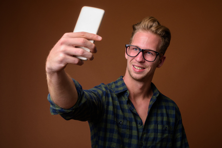 Studio shot of young handsome man against brown backgroundの写真素材