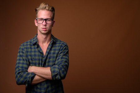 Studio shot of young handsome man against brown backgroundの写真素材