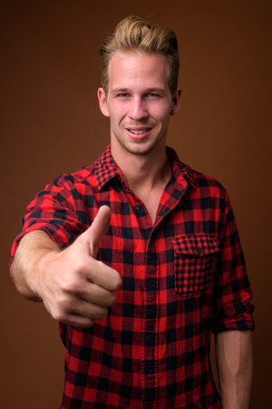 Studio shot of young handsome man against brown backgroundの写真素材