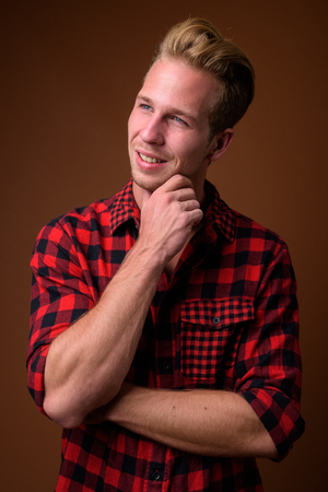Studio shot of young handsome man against brown backgroundの写真素材