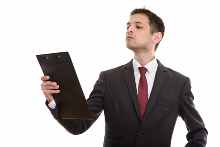 Studio shot of young businessman reading on clipboardの写真素材