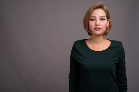 Portrait of beautiful Asian businesswoman against gray backgroundの写真素材