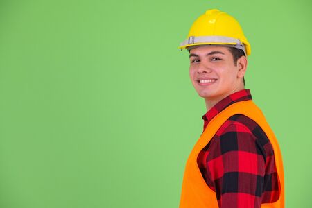Profile view of happy young multi ethnic man construction worker looking at camera
