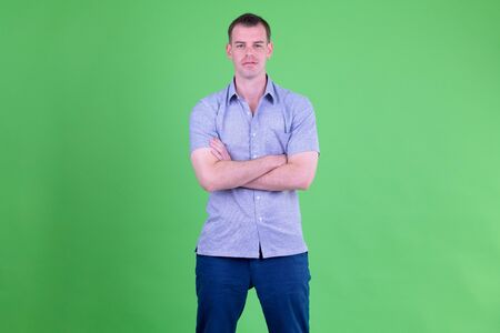 Portrait of businessman with arms crossed against green backgroundの写真素材
