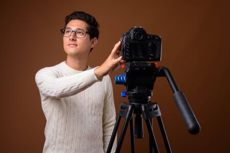 Young multi-ethnic handsome man against brown