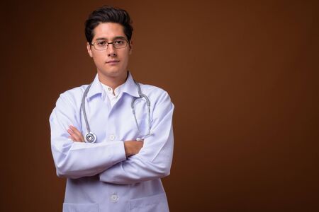 Young multi-ethnic handsome man doctor against brownの写真素材