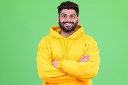 Happy young overweight bearded Indian man smiling with arms crossedの写真素材