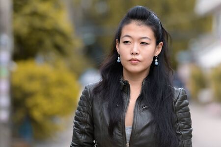 Face of beautiful Asian rebellious woman thinking outdoors