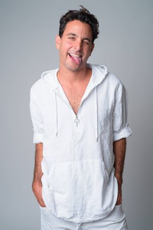 Portrait of happy handsome Hispanic man sticking tongue out