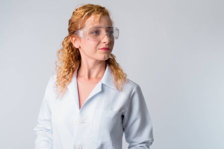 Face of beautiful blonde woman doctor with protective glasses thinking