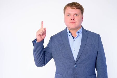 Portrait of overweight businessman in suit pointing upの写真素材