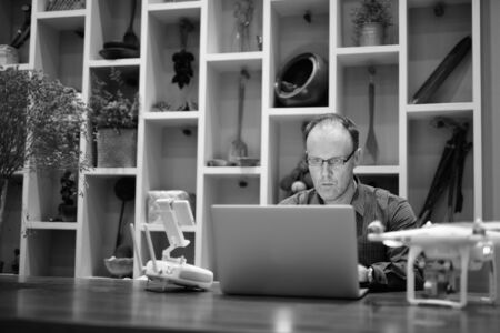 Mature man with camera drone using laptop computer