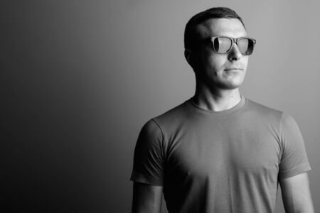Man wearing t-shirt and sunglasses against gray background